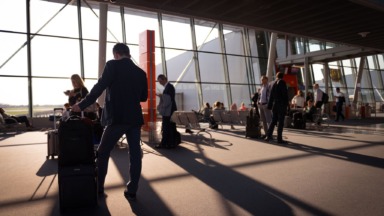 Travellers with wheeled cabin bags in an airport terminal